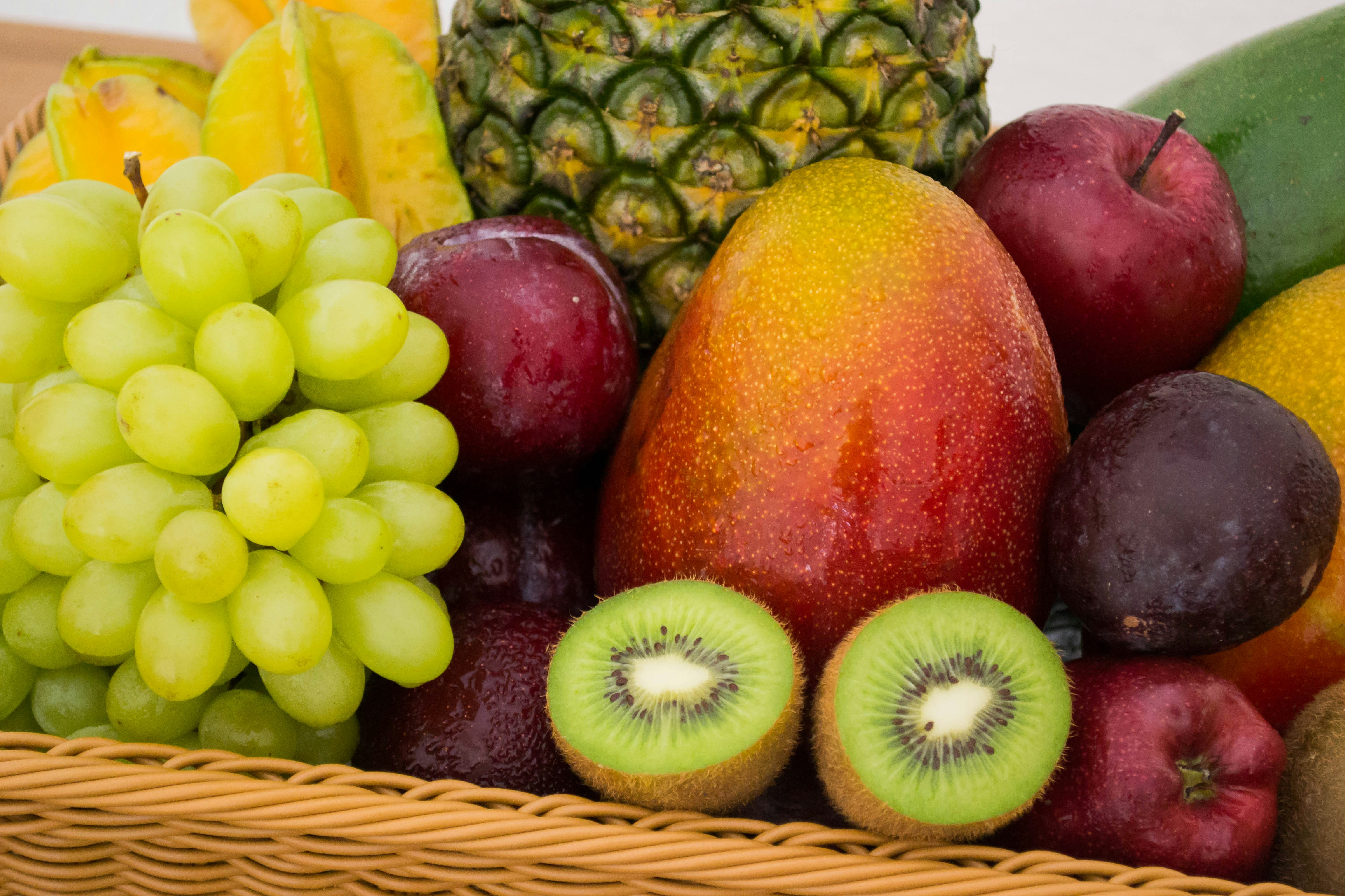 Different fruits including grapes, plums, mango, kiwis and oranges